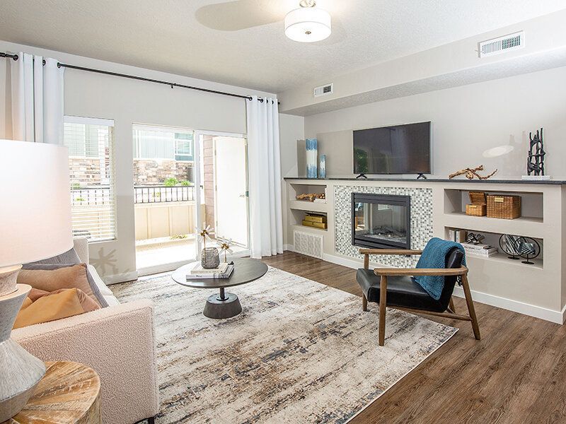 Living room in an apartment with sofa, chair, coffee table, fireplace, and TV.