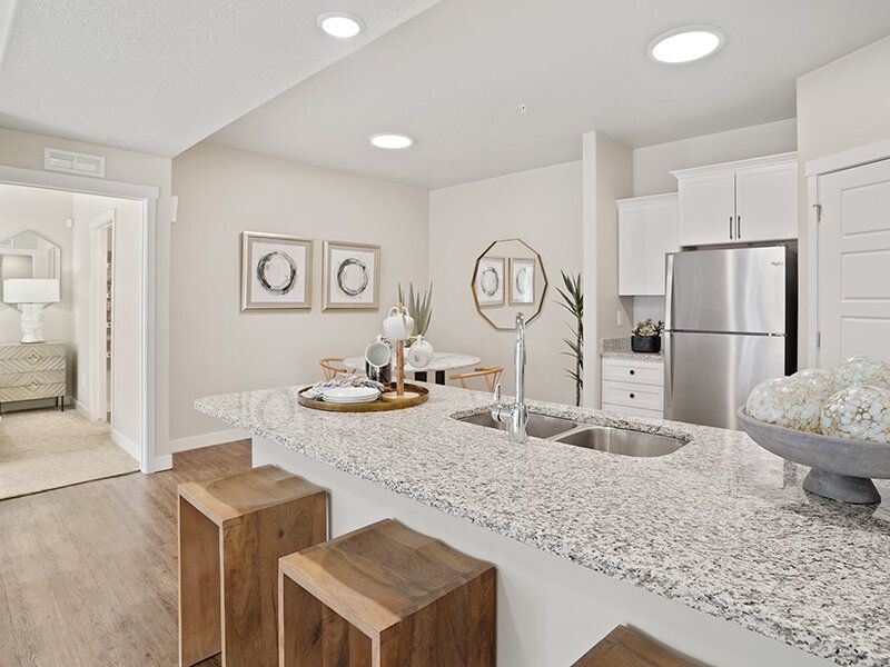 Open-concept kitchen with granite island, bar stools, and stainless-steel appliances.