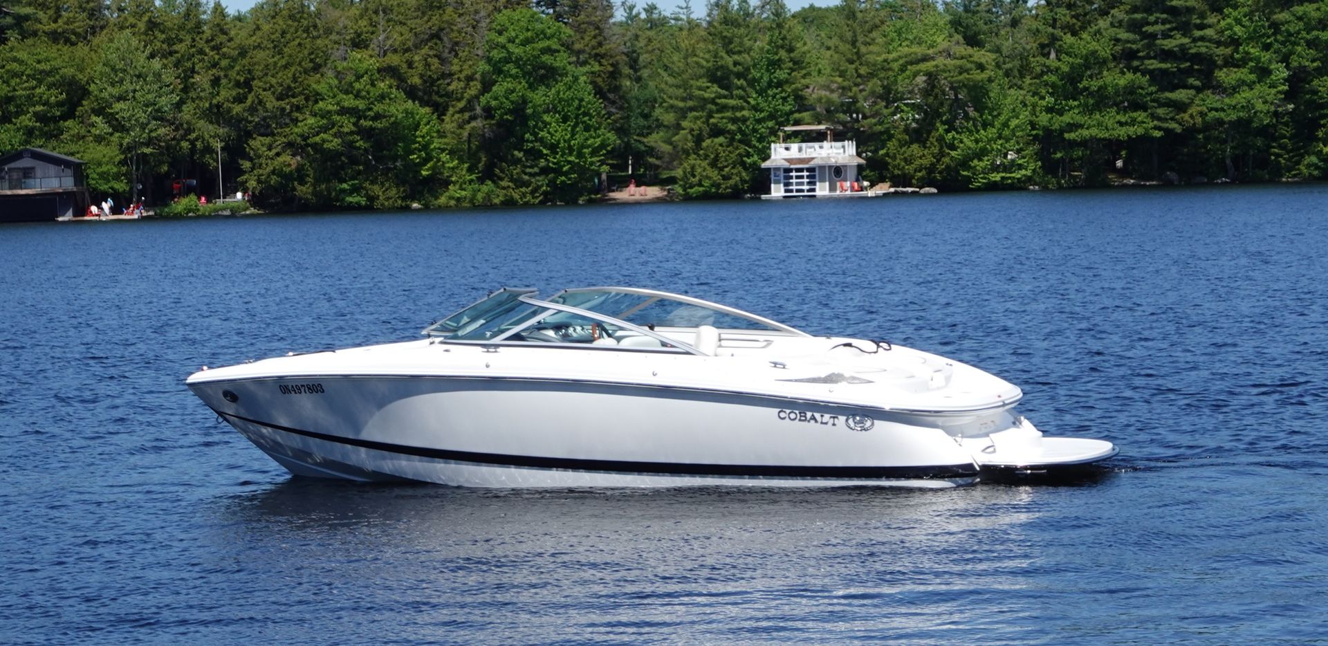 White speedboat on a trailer in a sunny parking lot
