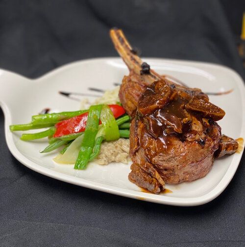 A white plate topped with meat and vegetables on a table.