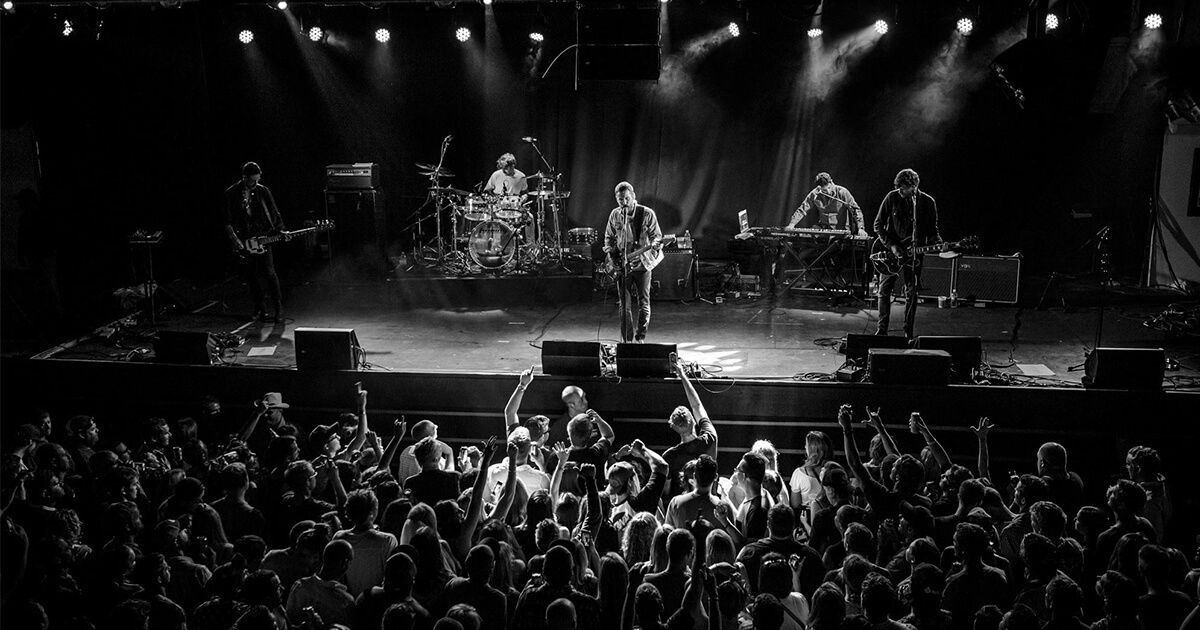 A group of people are playing instruments on a stage in front of a crowd.