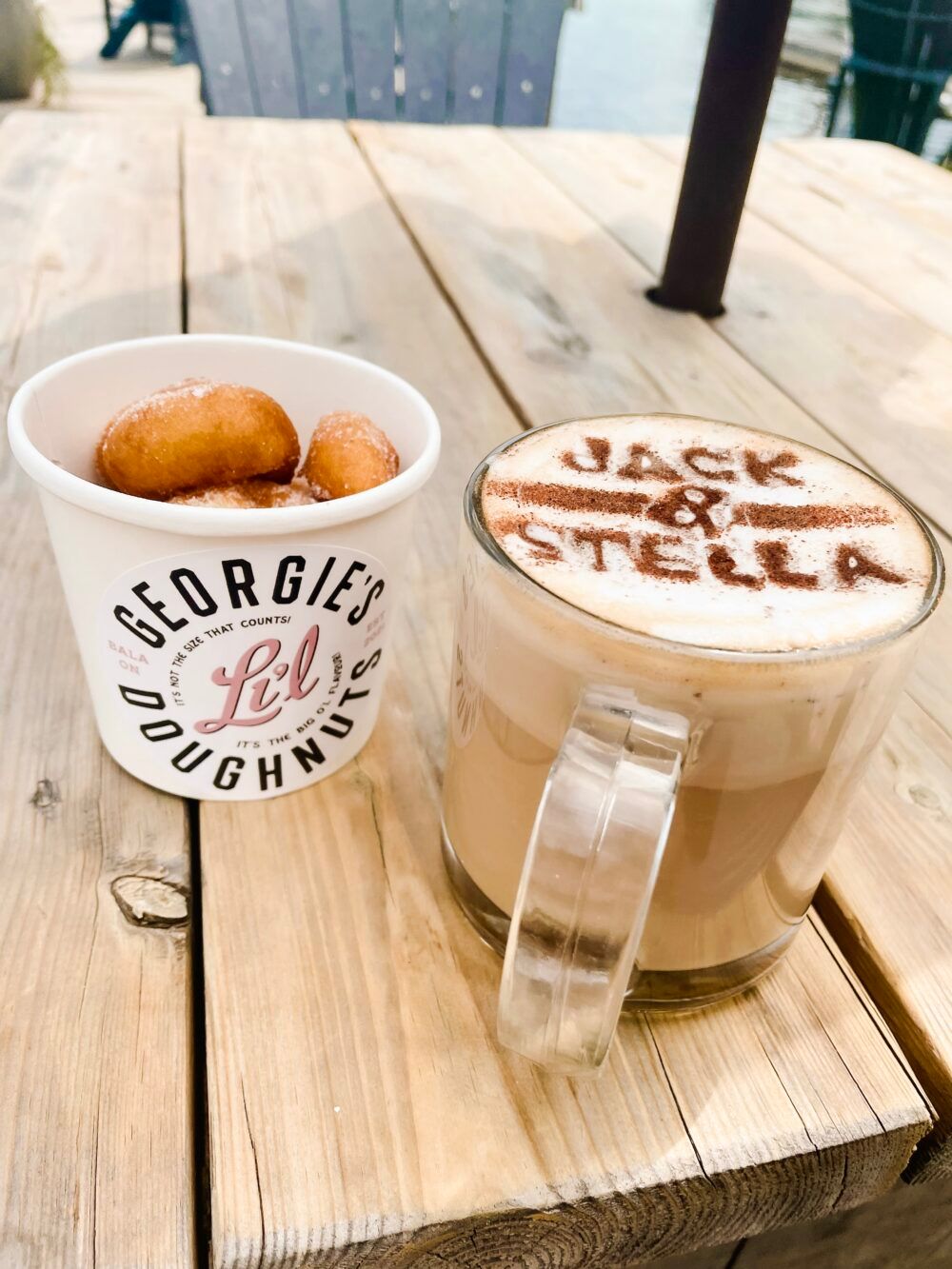 A cup of donuts and a cup of coffee on a wooden table.