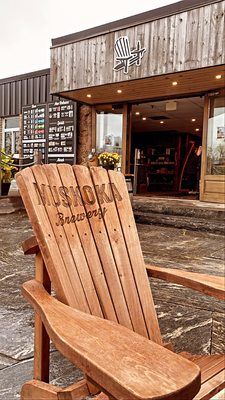 A wooden chair is sitting in front of a building.