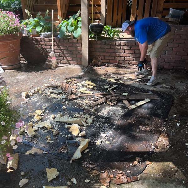 a man is working on removing a patio with a brick wall in the background