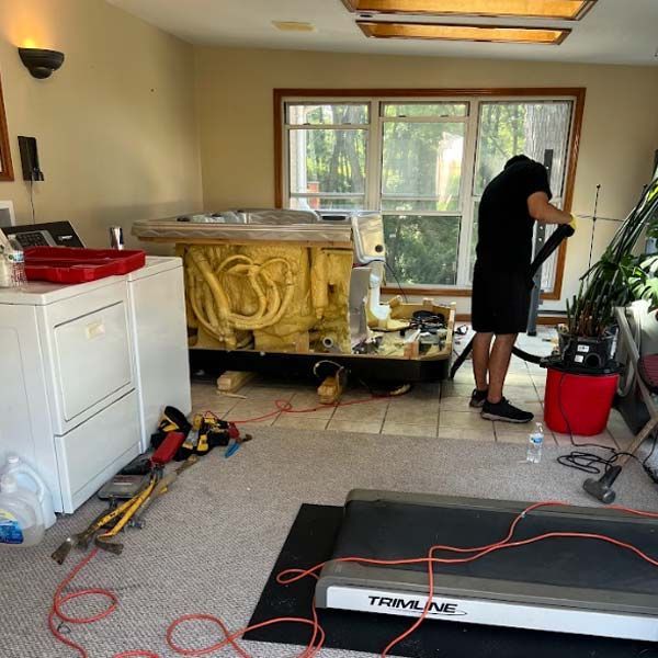 a man is working on a hot tub removal in a room