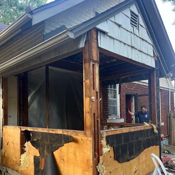 a man is working on the porch of a house that is being demolished