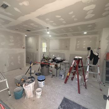 Room under renovation with drywall and tools.