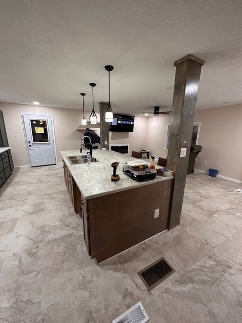 Modern open-plan living space with kitchen island, living area, and balcony access. Natural light floods the area.