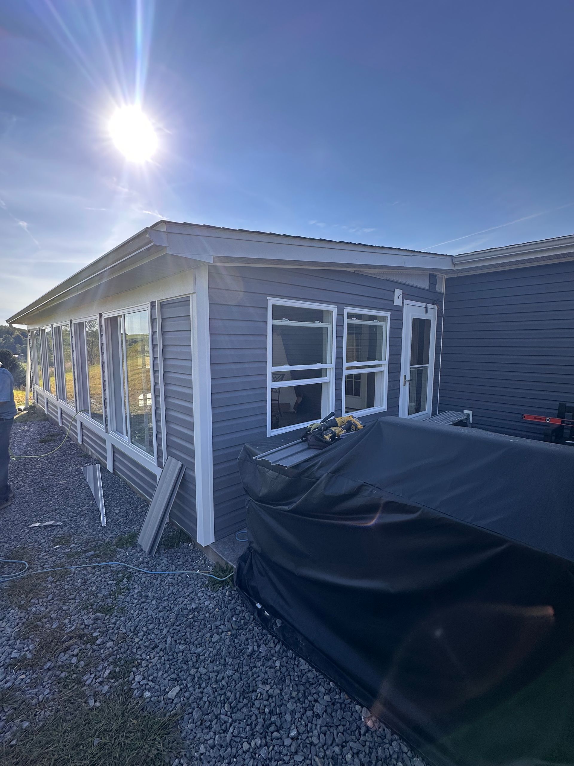 White house with gray roof, small front porch, two windows, bushes along the front.