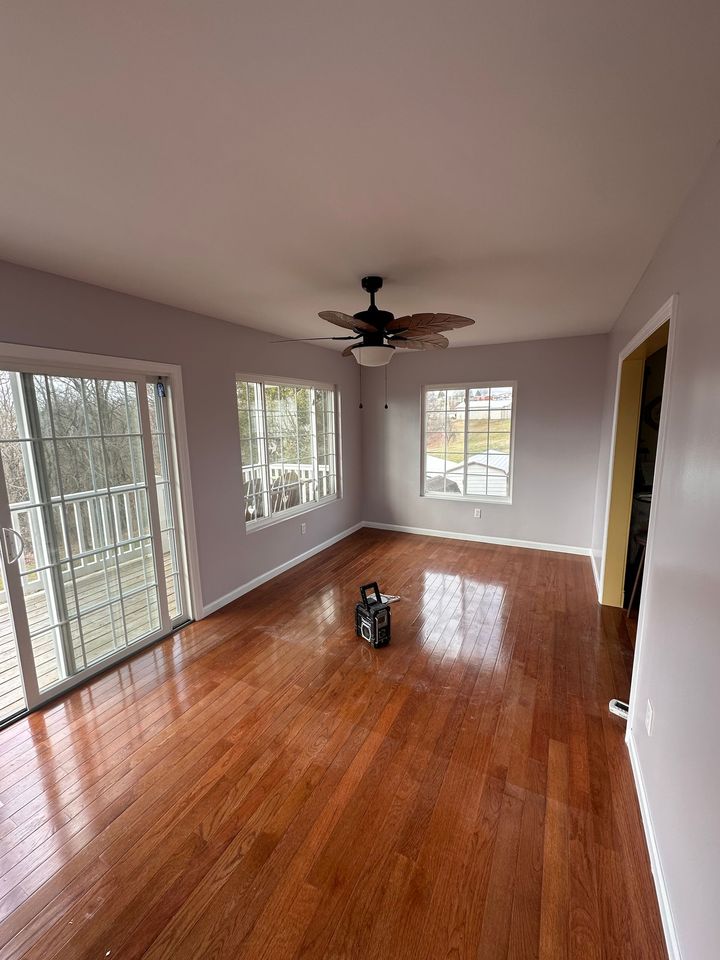 Two people installing dark blue kitchen cabinets in a newly renovated kitchen with white countertops and island.