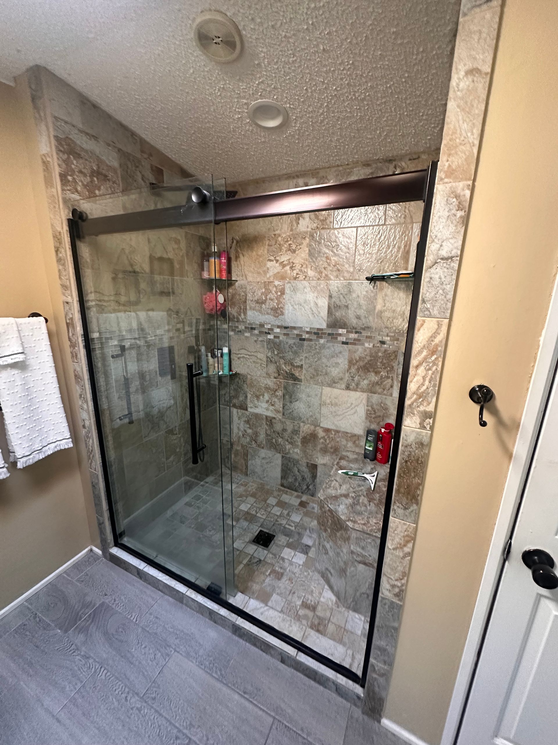Modern bathroom with large glass shower, double vanity, and gray walls.
