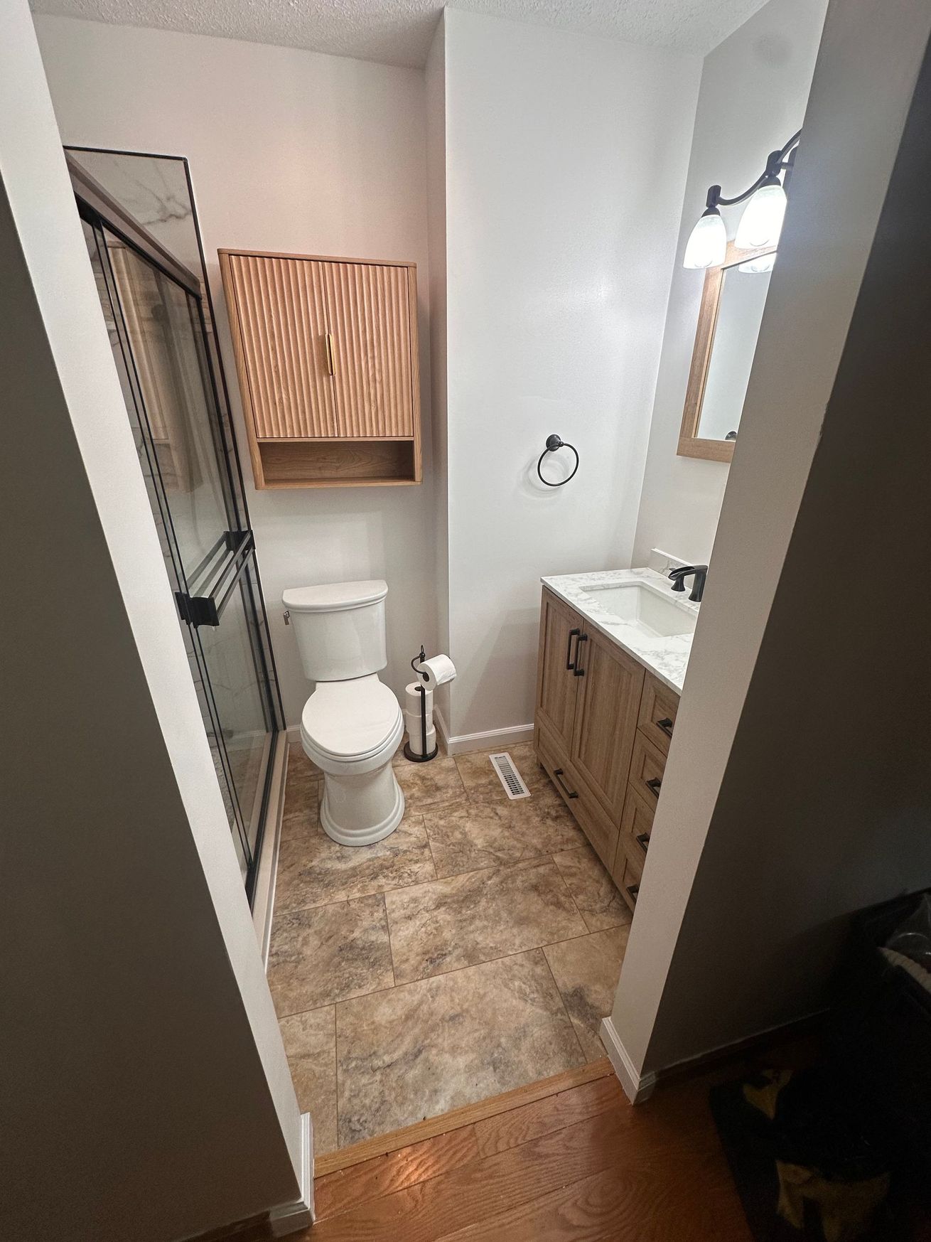 Modern bathroom with a glass shower, wooden double vanity, and large mirror.