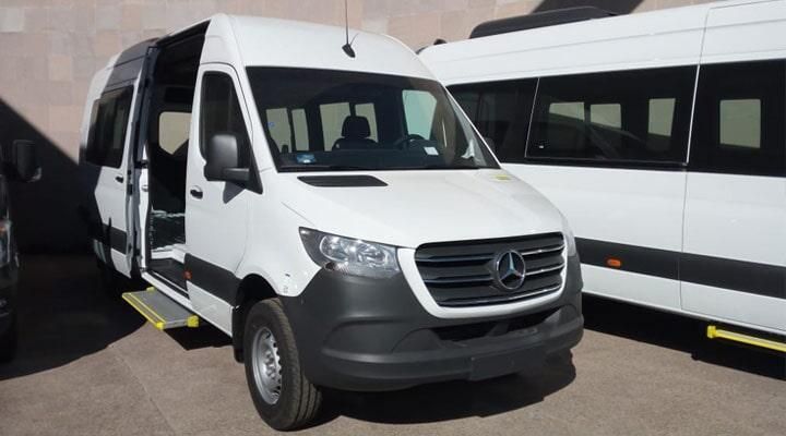 Una furgoneta blanca con la puerta abierta está estacionada al lado de otra furgoneta.