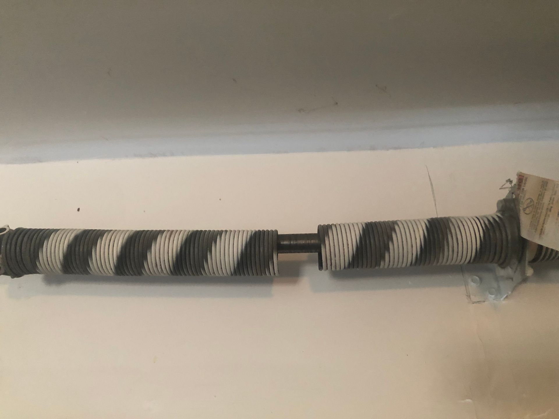 A black and white striped spring is hanging on a white wall.