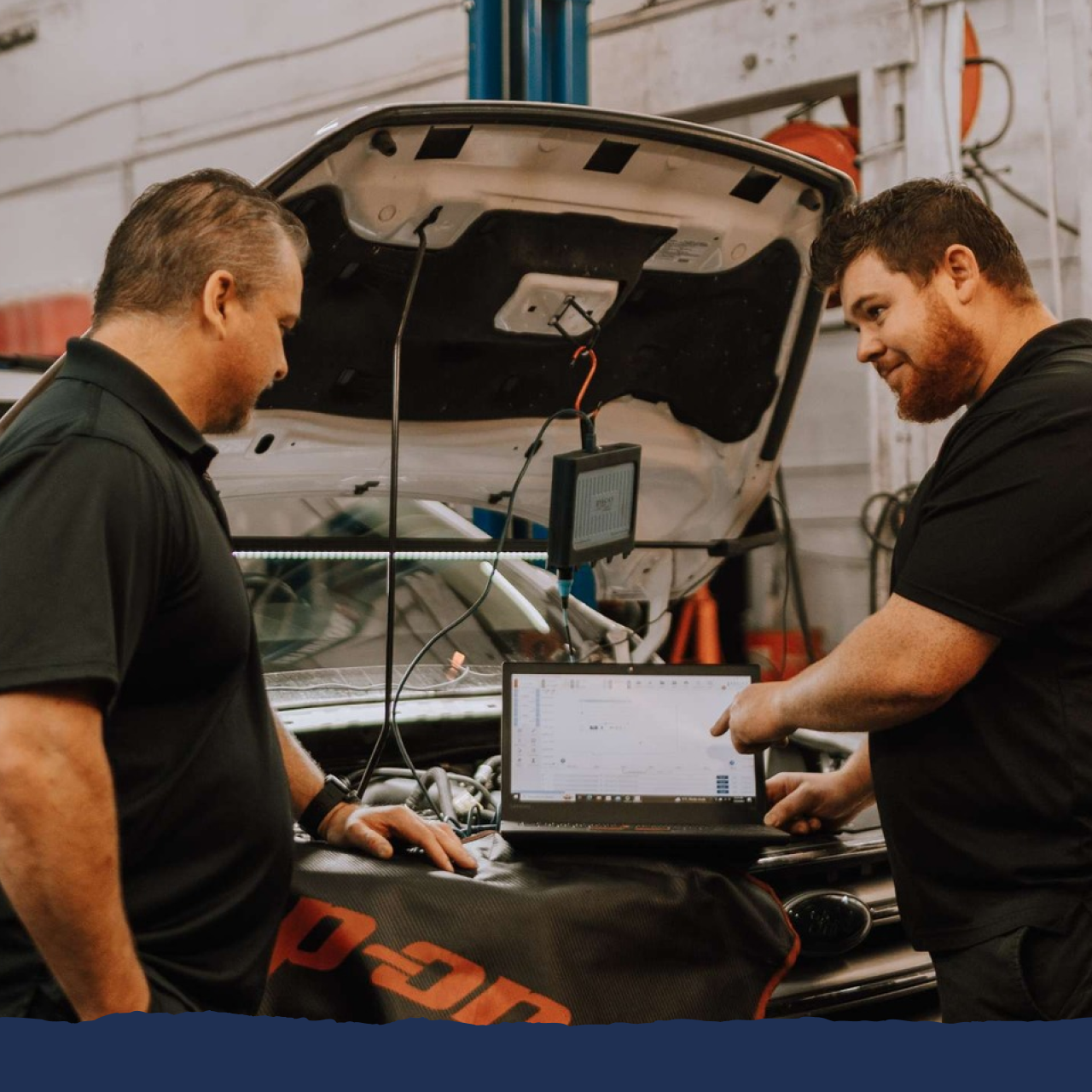 Two men looking at a laptop in front of a snap on bag | Silvhorn Automotive