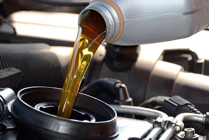 A bottle of oil is being poured into a car engine | Silvhorn Automotive