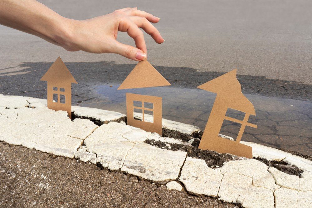 A Person is Holding a Cardboard House With an Arrow Pointing Up — Optimus 1 Insurance Brokers in  Brisbane, QLD