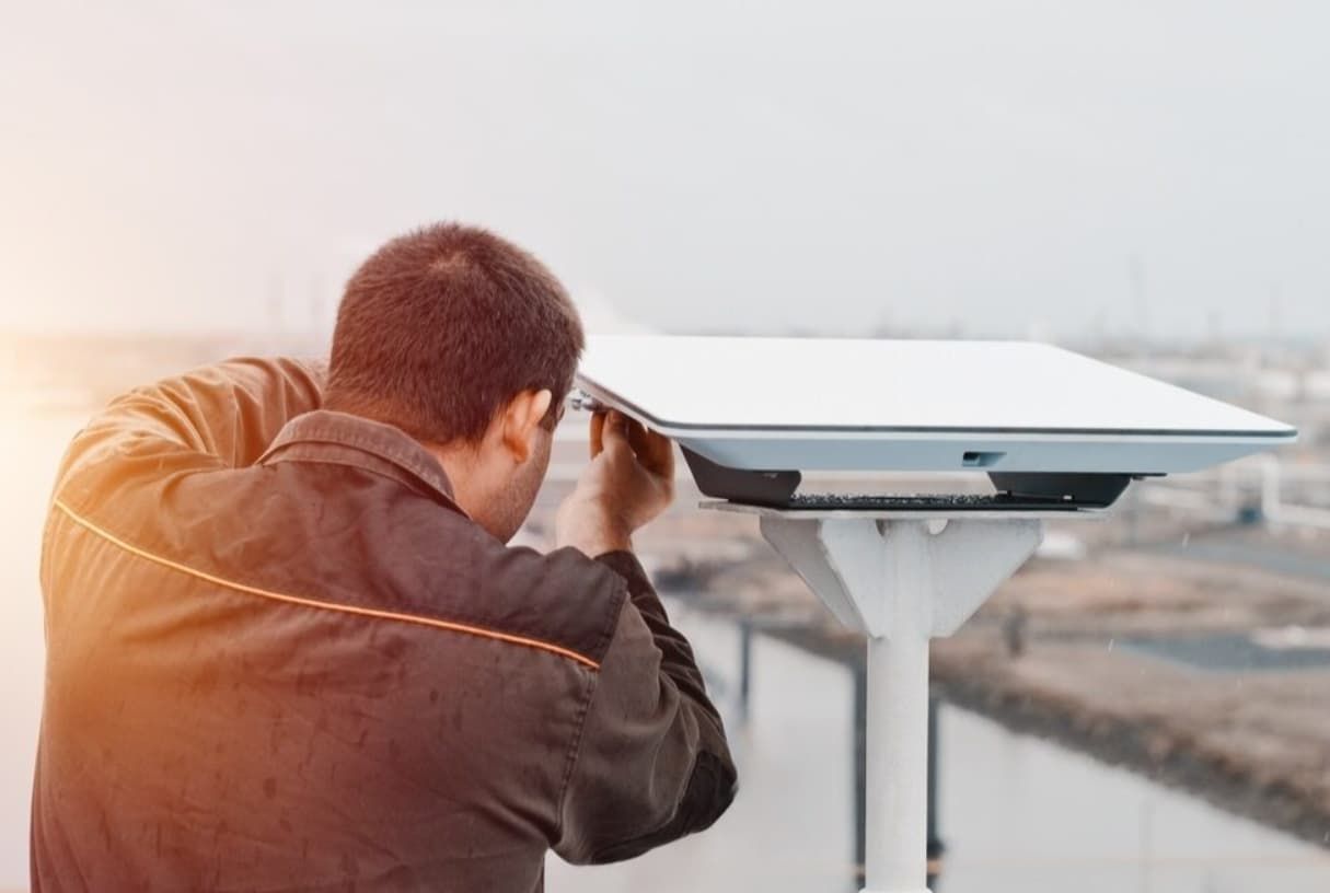 A Man Is Looking Through A Telescope On Top Of A Building — Capricorn Communications in Emerald, QLD