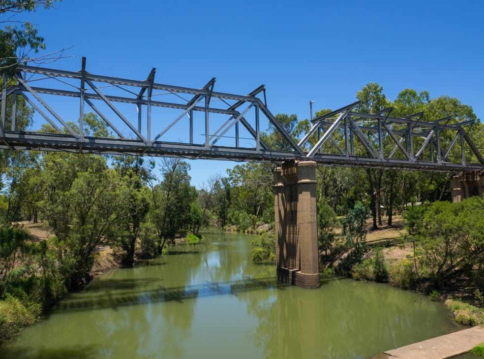 A Bridge Over A River Surrounded By Trees On A Sunny Day — Capricorn Communications in Emerald, QLD