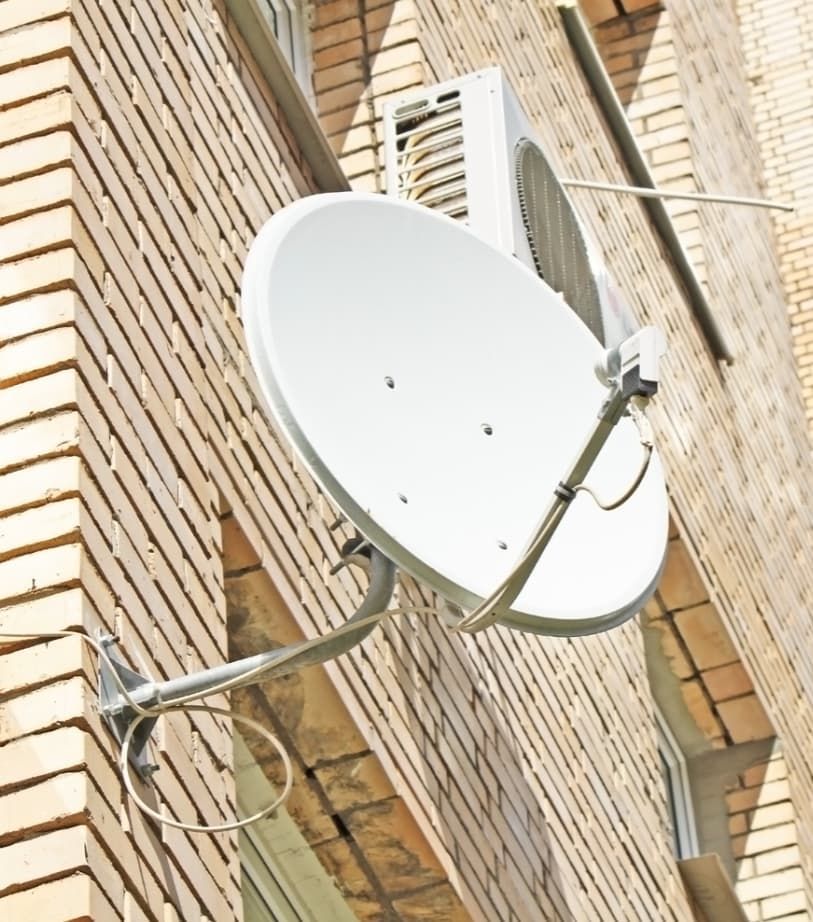 A Satellite Dish Is Attached To The Side Of A Brick Building — Capricorn Communications in Biloela, QLD