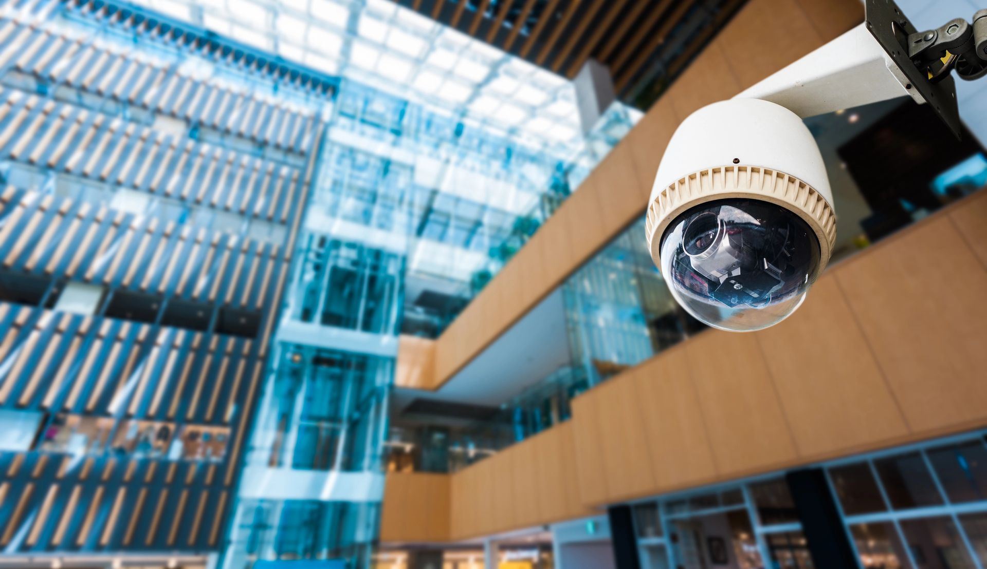 A security camera is hanging from the ceiling of a large building.