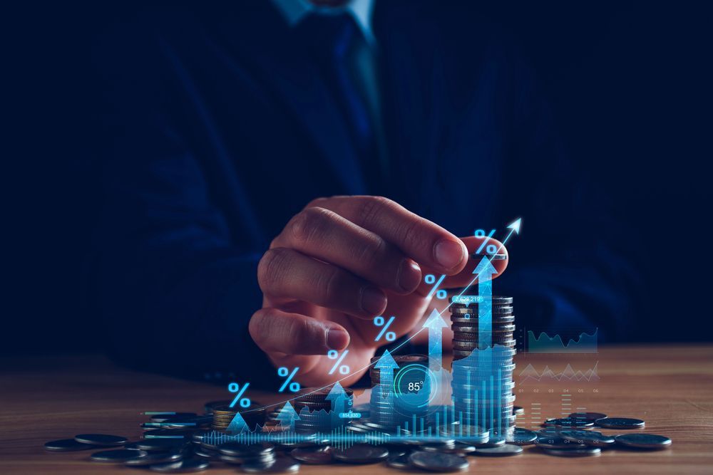 A person's hand hovering over a financial chart indicating growth with a pile of coins.