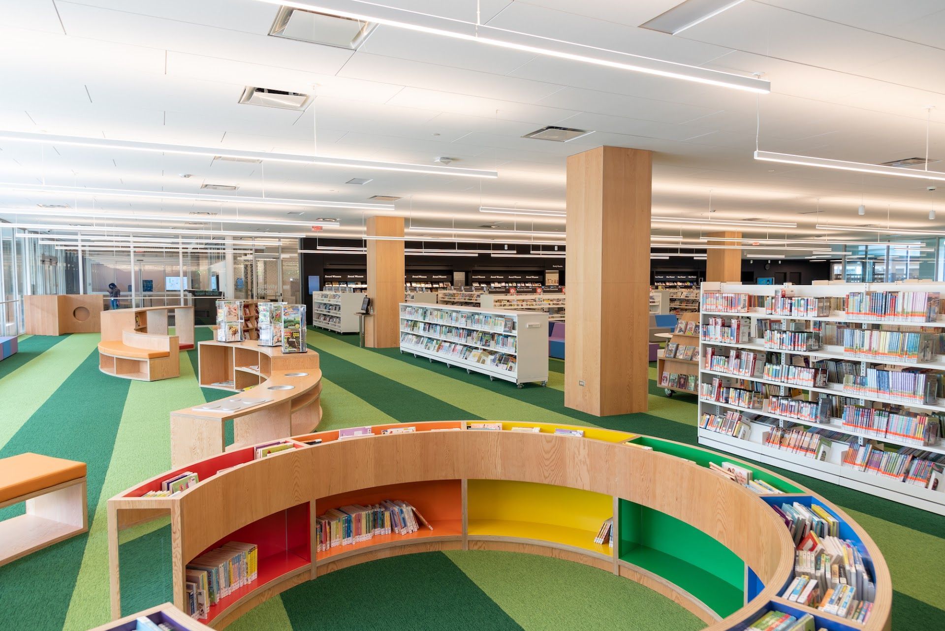 A library with a lot of books on shelves and a green carpet.