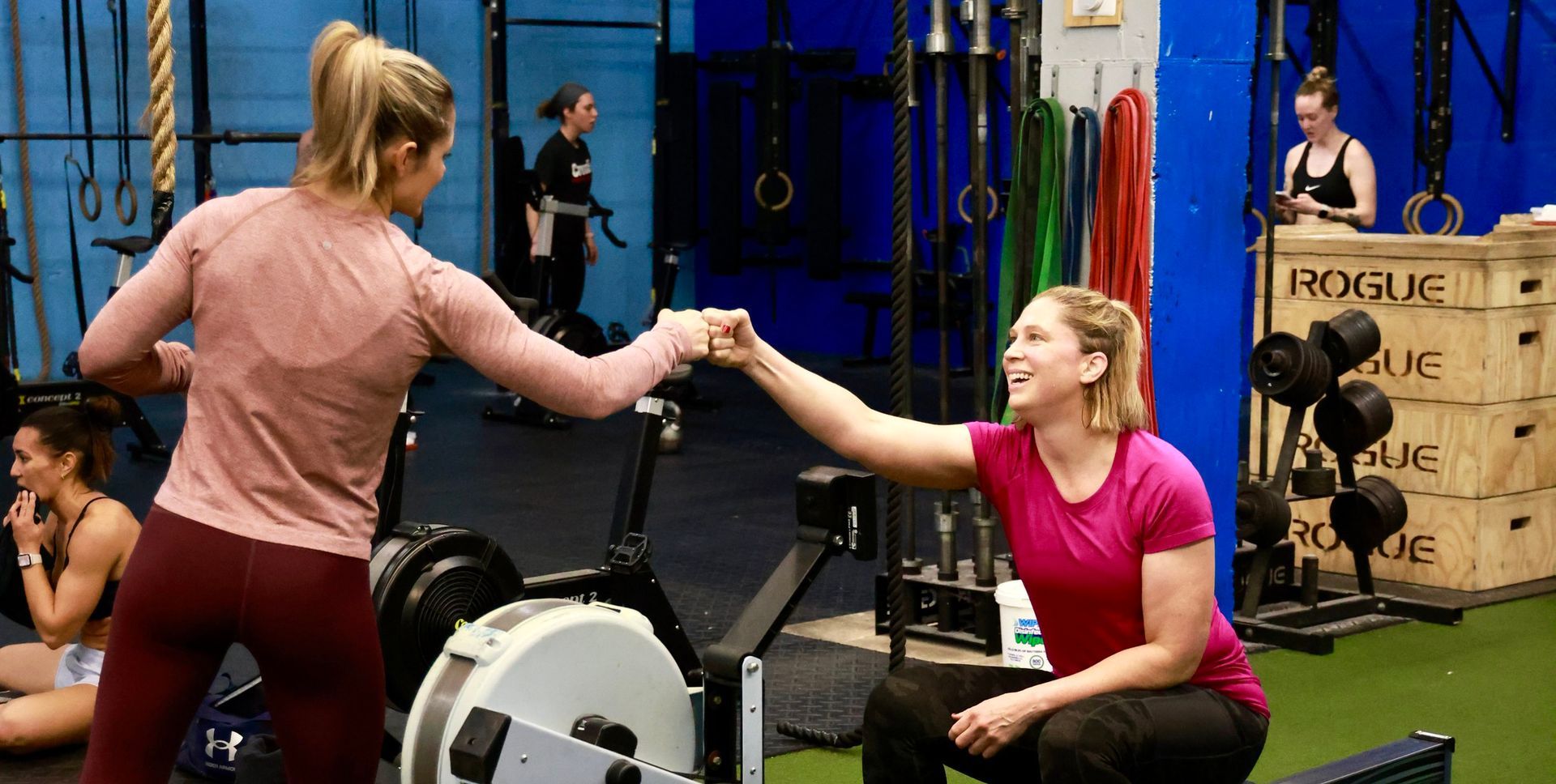 Two women are giving each other a high five in a gym.