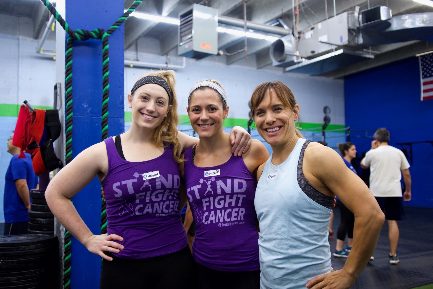 Three women are posing for a picture in a gym.