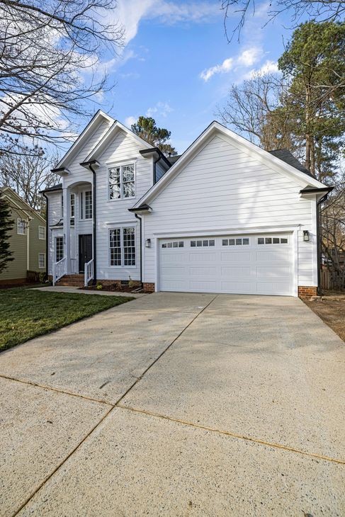 A large white house with a white garage door and a driveway.