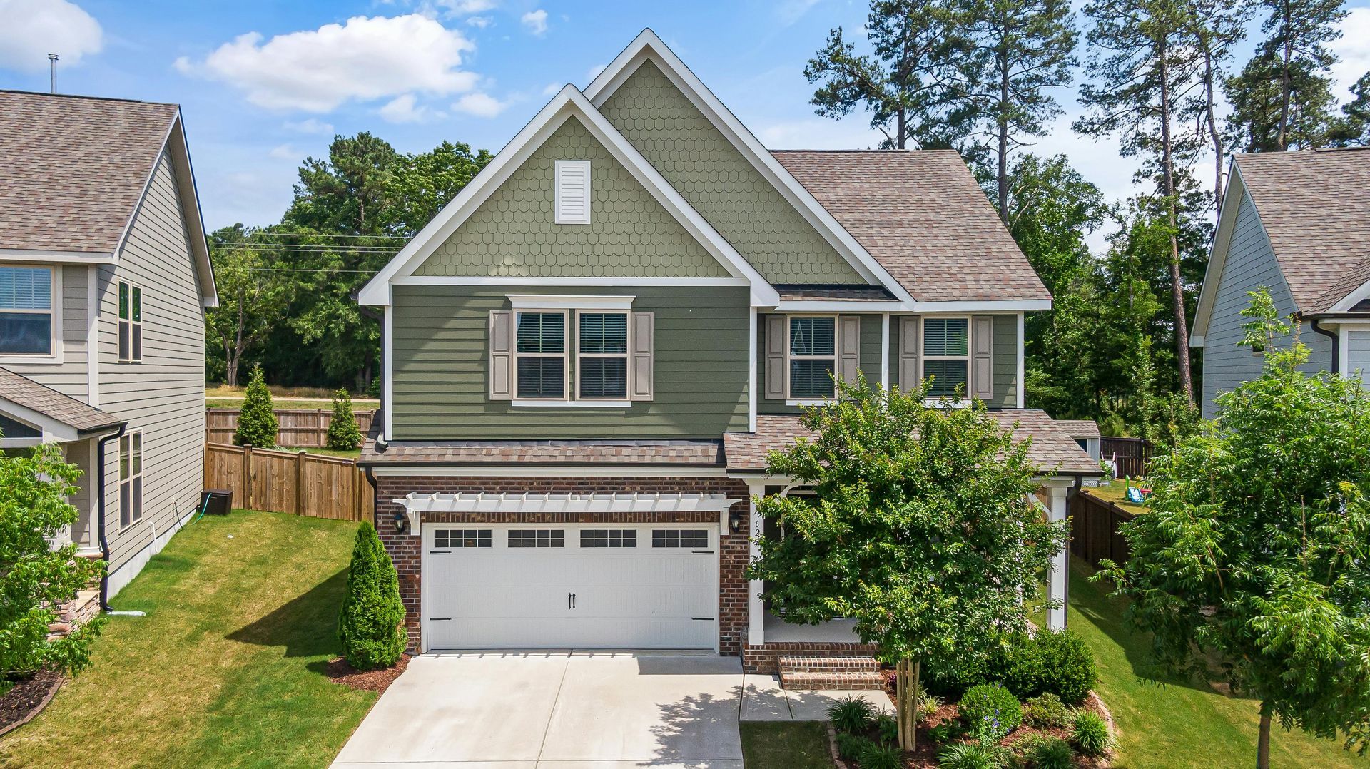 An aerial view of a house with a green siding and a white garage door.