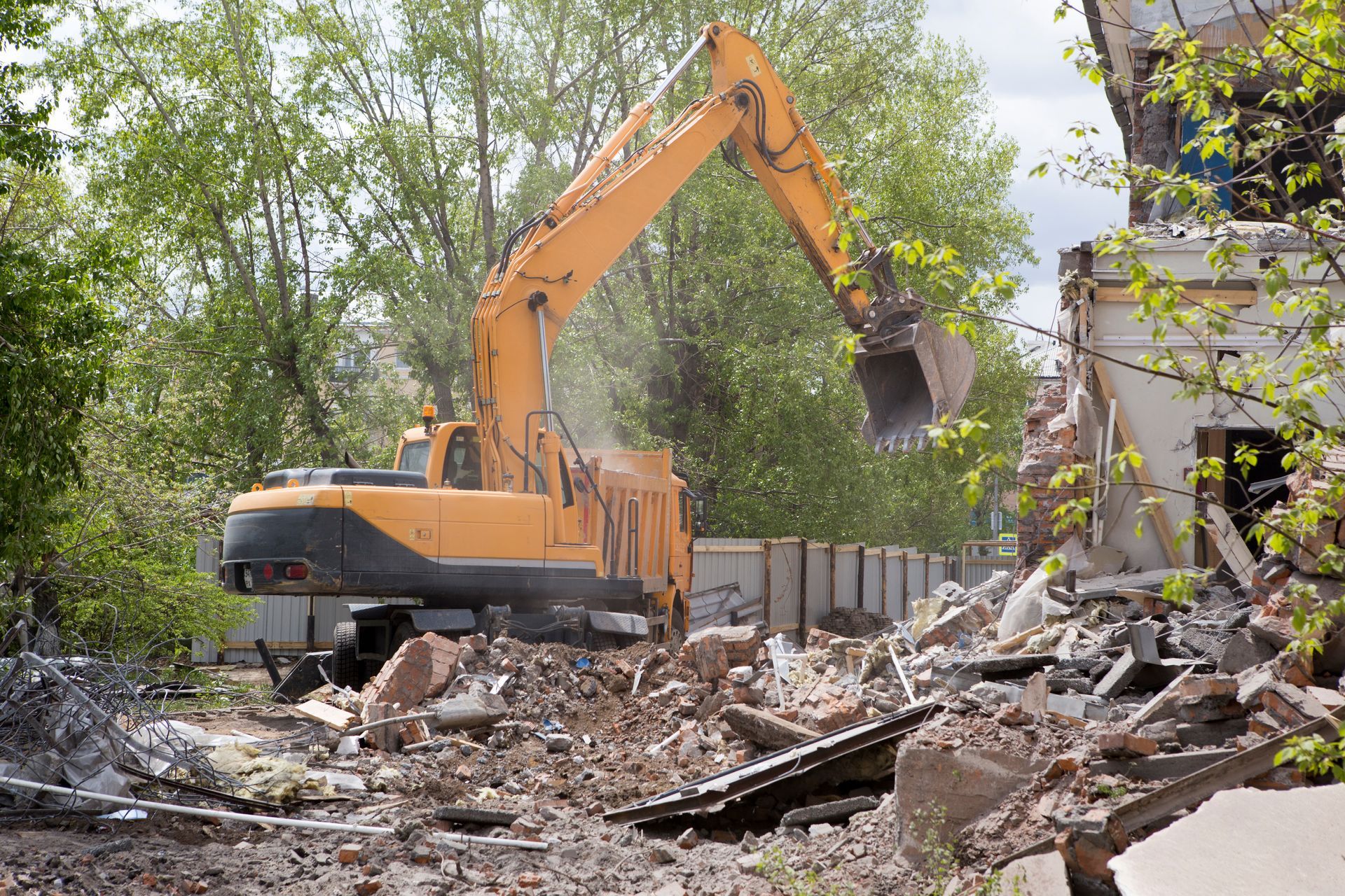 A large yellow excavator is demolishing a building.