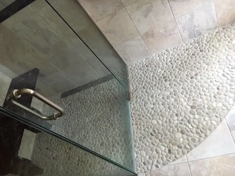 Shower with pebble tile floor and glass door.