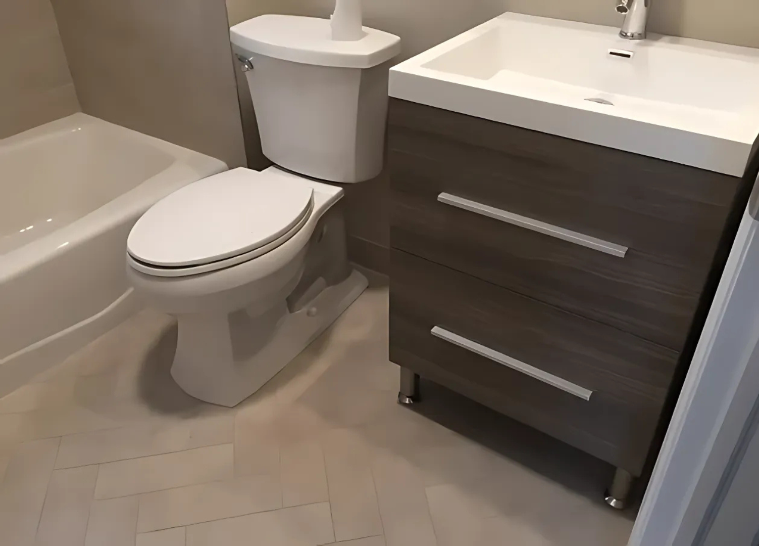 Bathroom with toilet, vanity with sink, and a bathtub. Light-colored walls and flooring.
