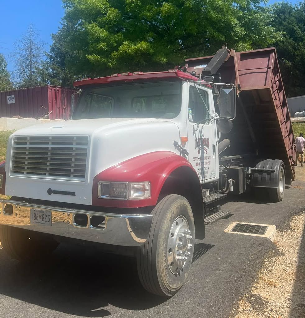 A red and white dump truck is parked on the side of the road.