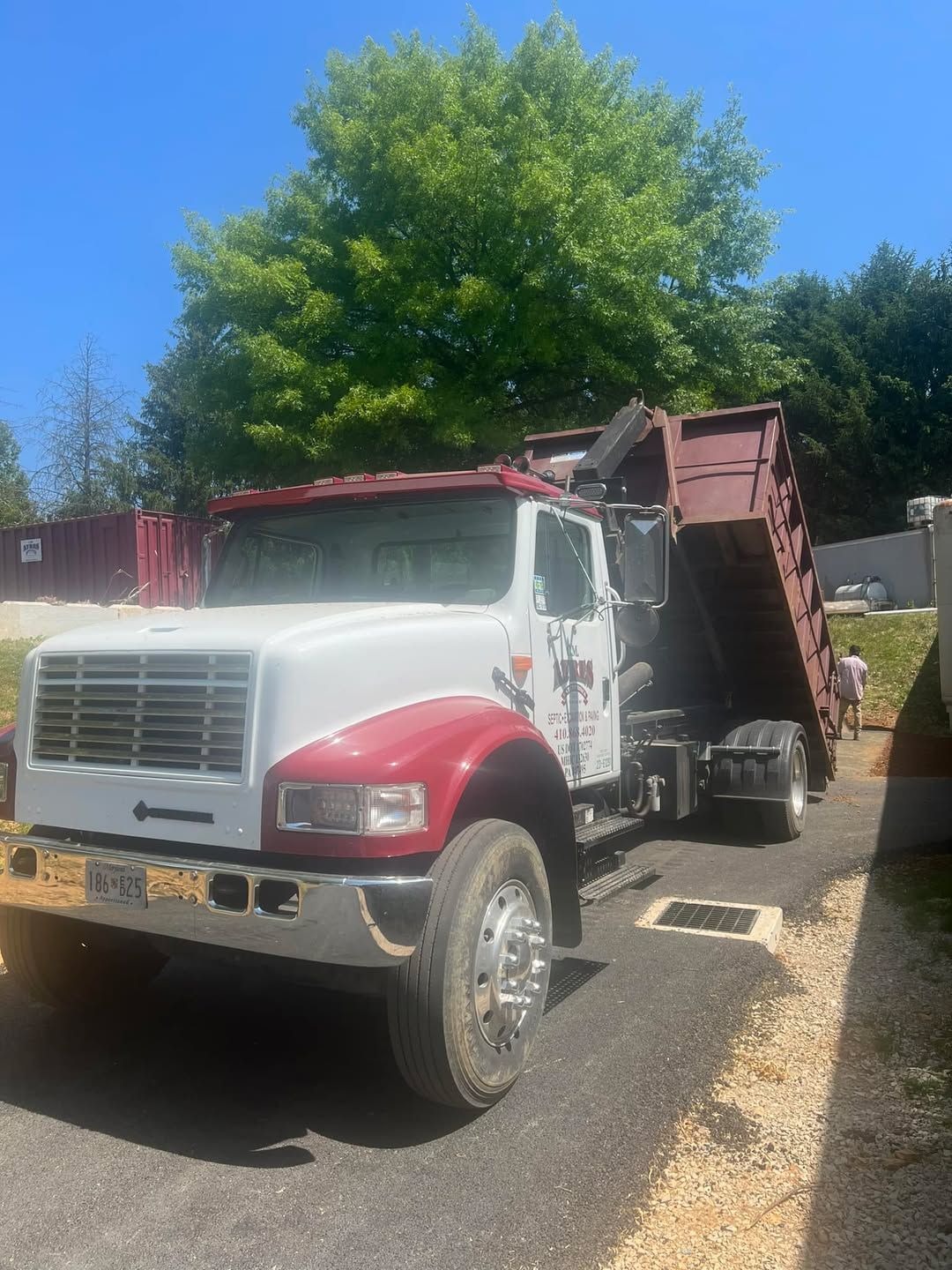 A red and white dump truck is parked on the side of the road.