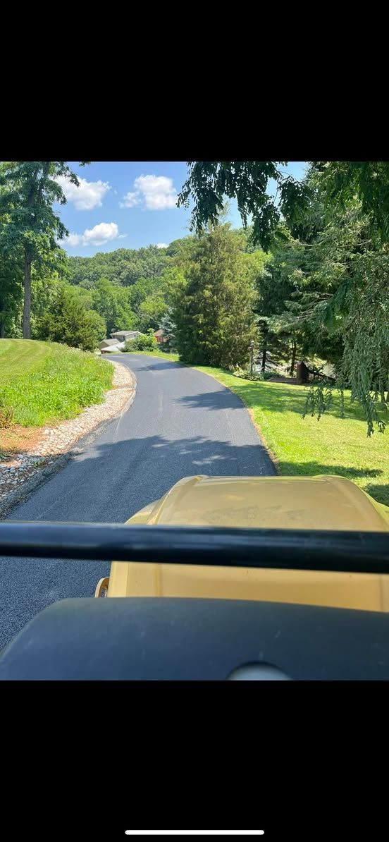 A car is driving down a road with trees on both sides.