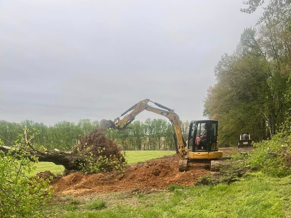 A yellow excavator is digging a hole in a field.