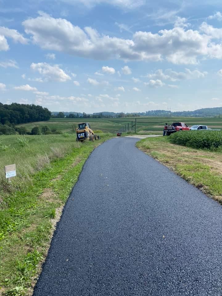 A newly paved road going through a grassy field.