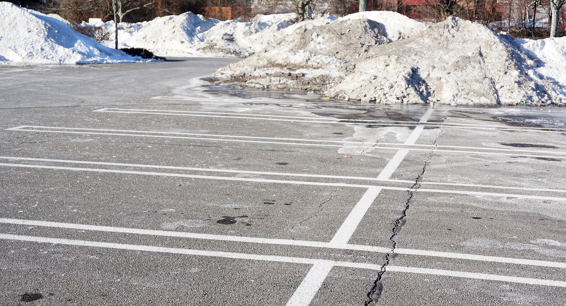 Snowy parking lot with melting snow and visible parking lines.