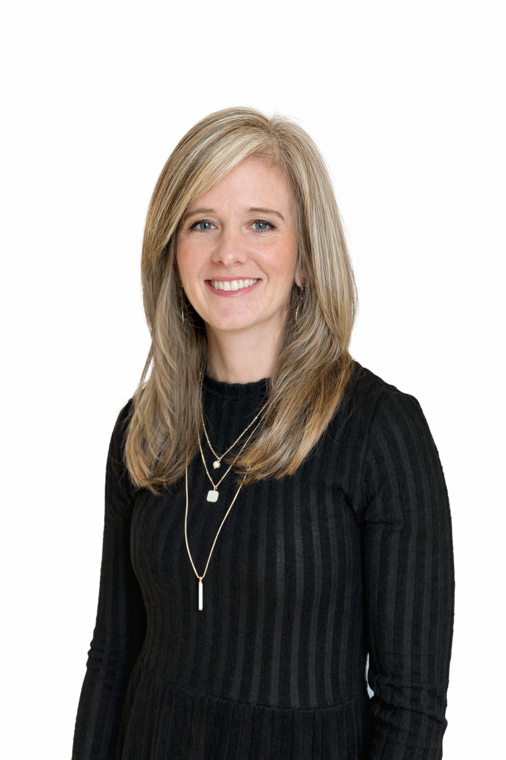 Woman with blonde hair wearing a black sweater smiles. She is in front of a white background.