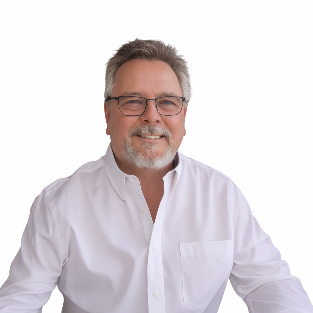 Man with glasses and grey beard smiling, wearing a white shirt, against a white background.