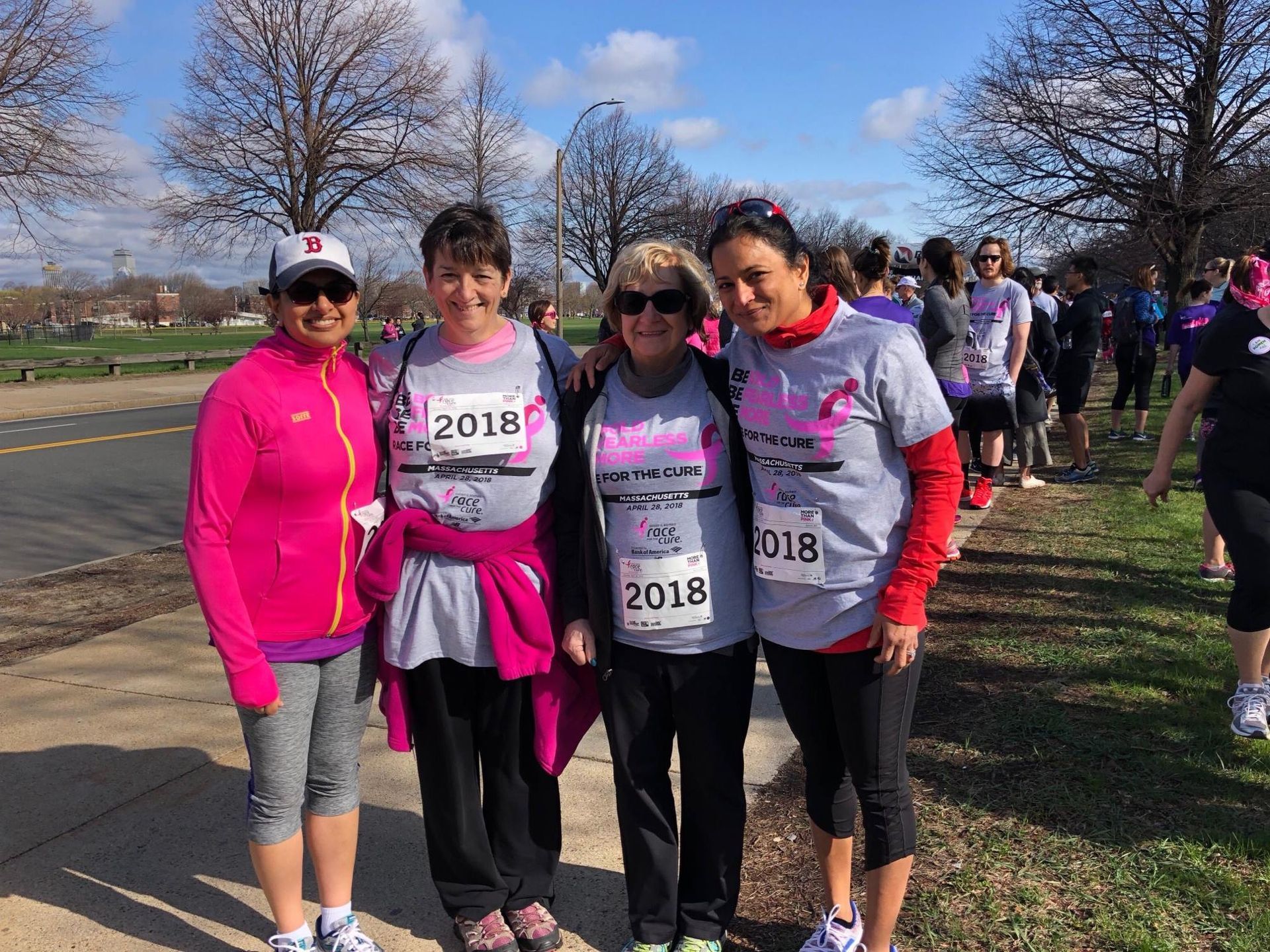 Four women smiling, wearing race shirts with