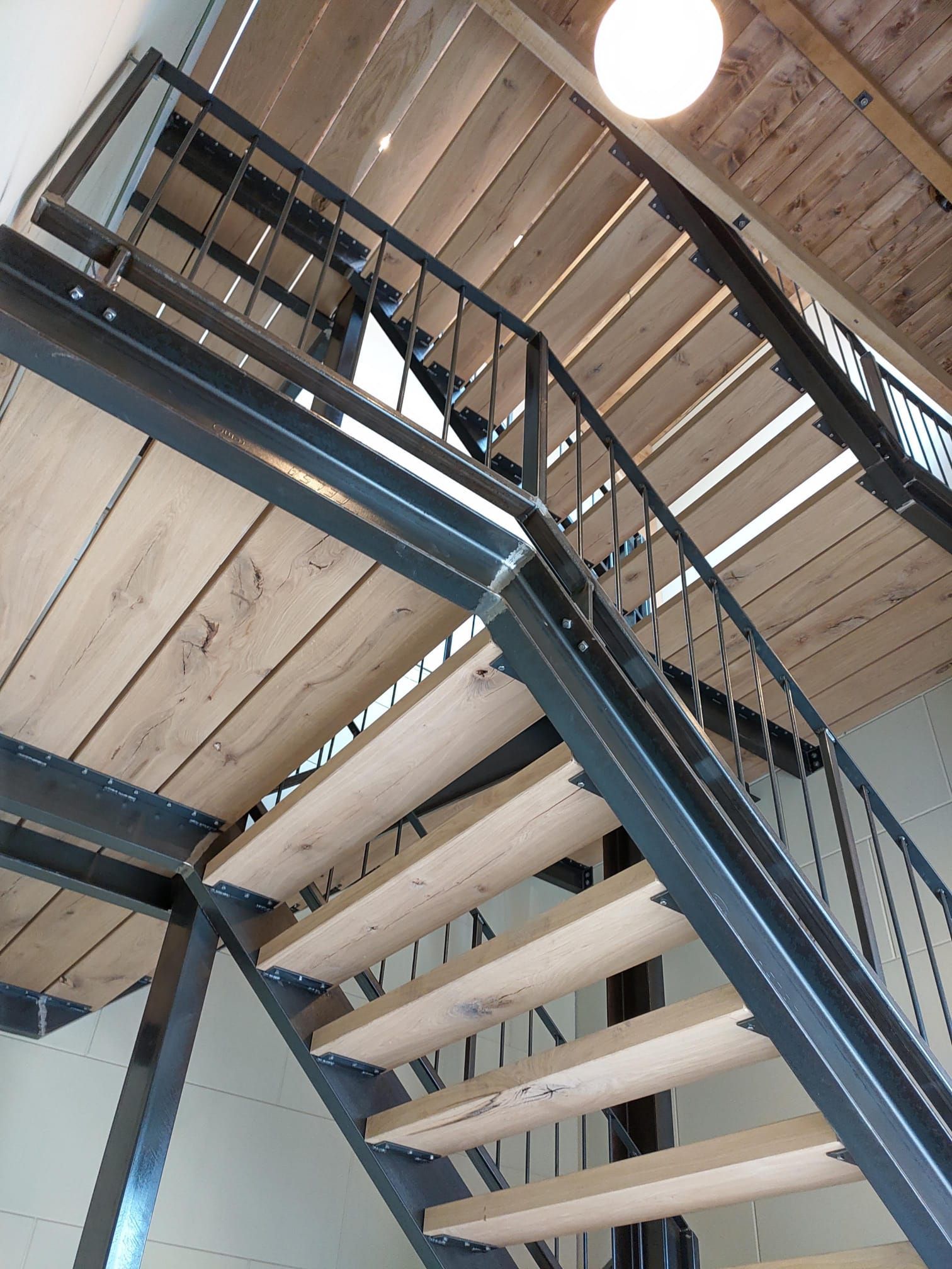 Een trap met een metalen leuning en houten treden