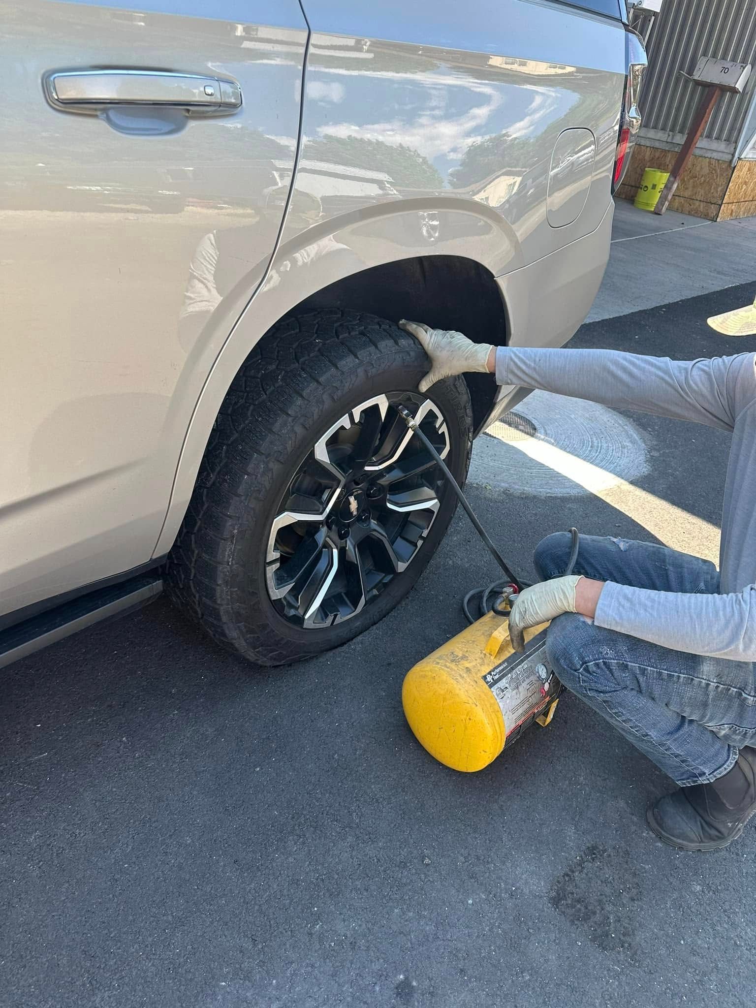 A person is changing a tire on a car in a parking lot.