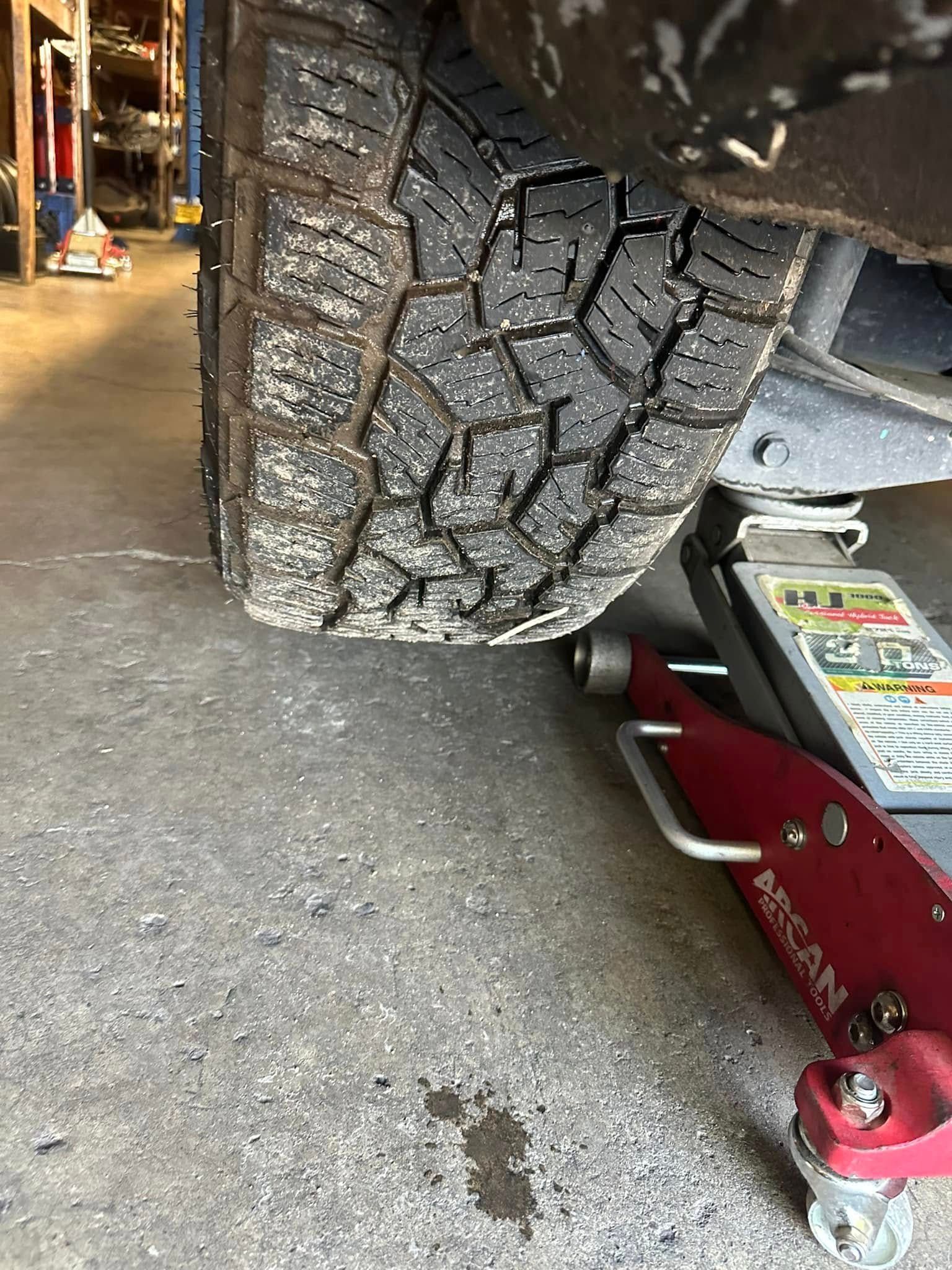 A close up of a tire on a jack in a garage.