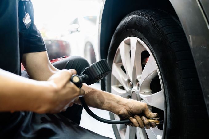 A man is pumping air into a car tire.