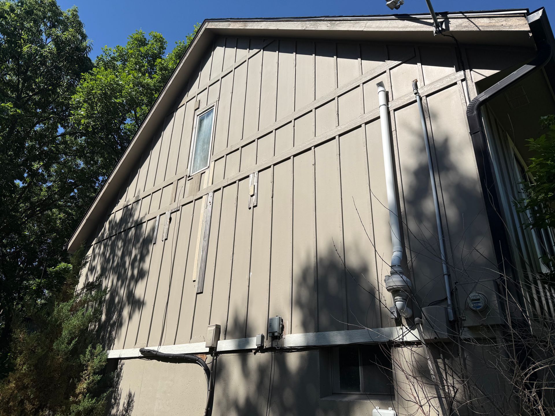 side of a brown house that's missing pieces of siding.