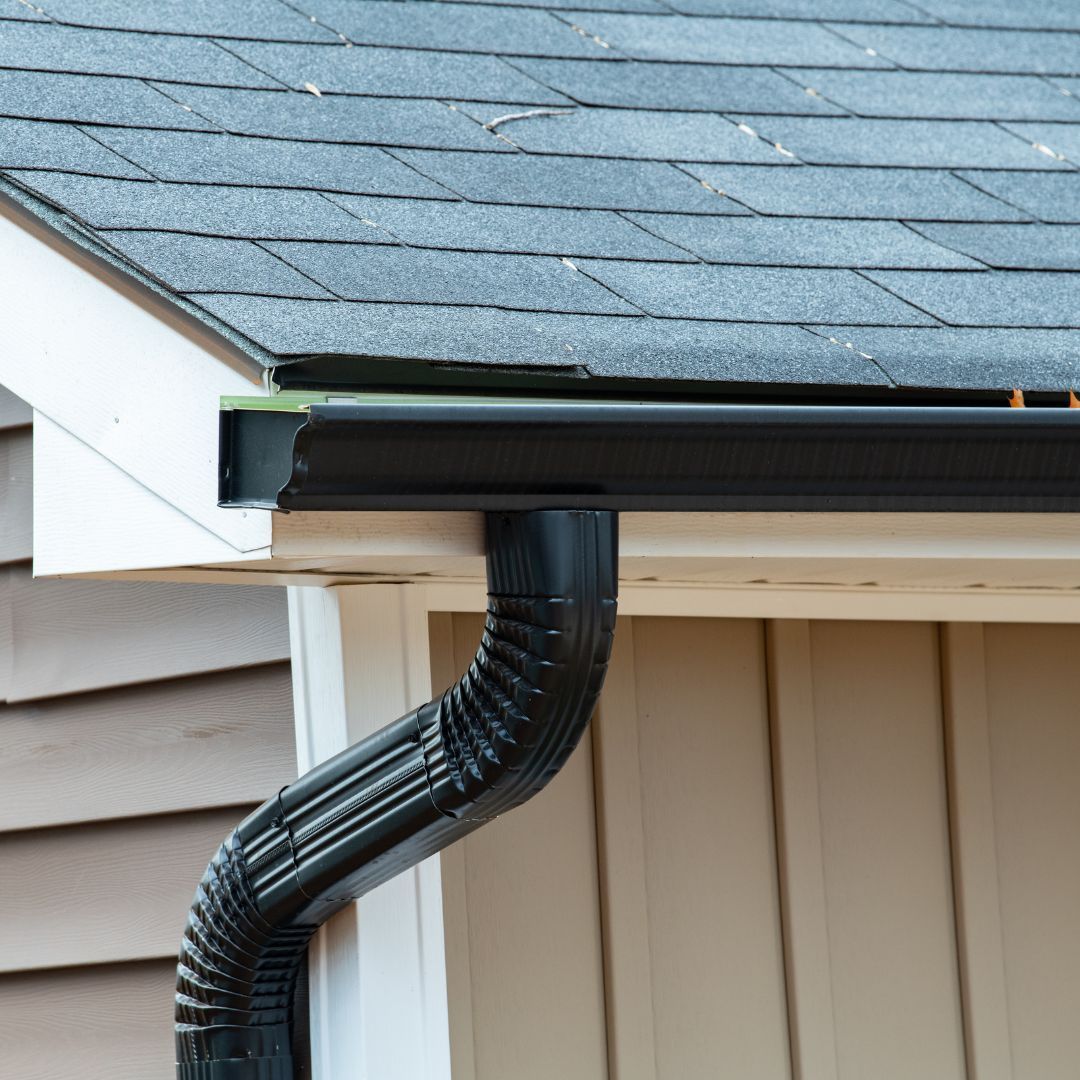 A black gutter is attached to the roof of a house