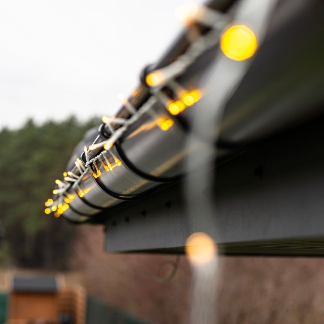 A close up of a gutter with christmas lights on it.
